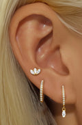 Gold earrings set with lotus stud and zirconia hoop on model ear